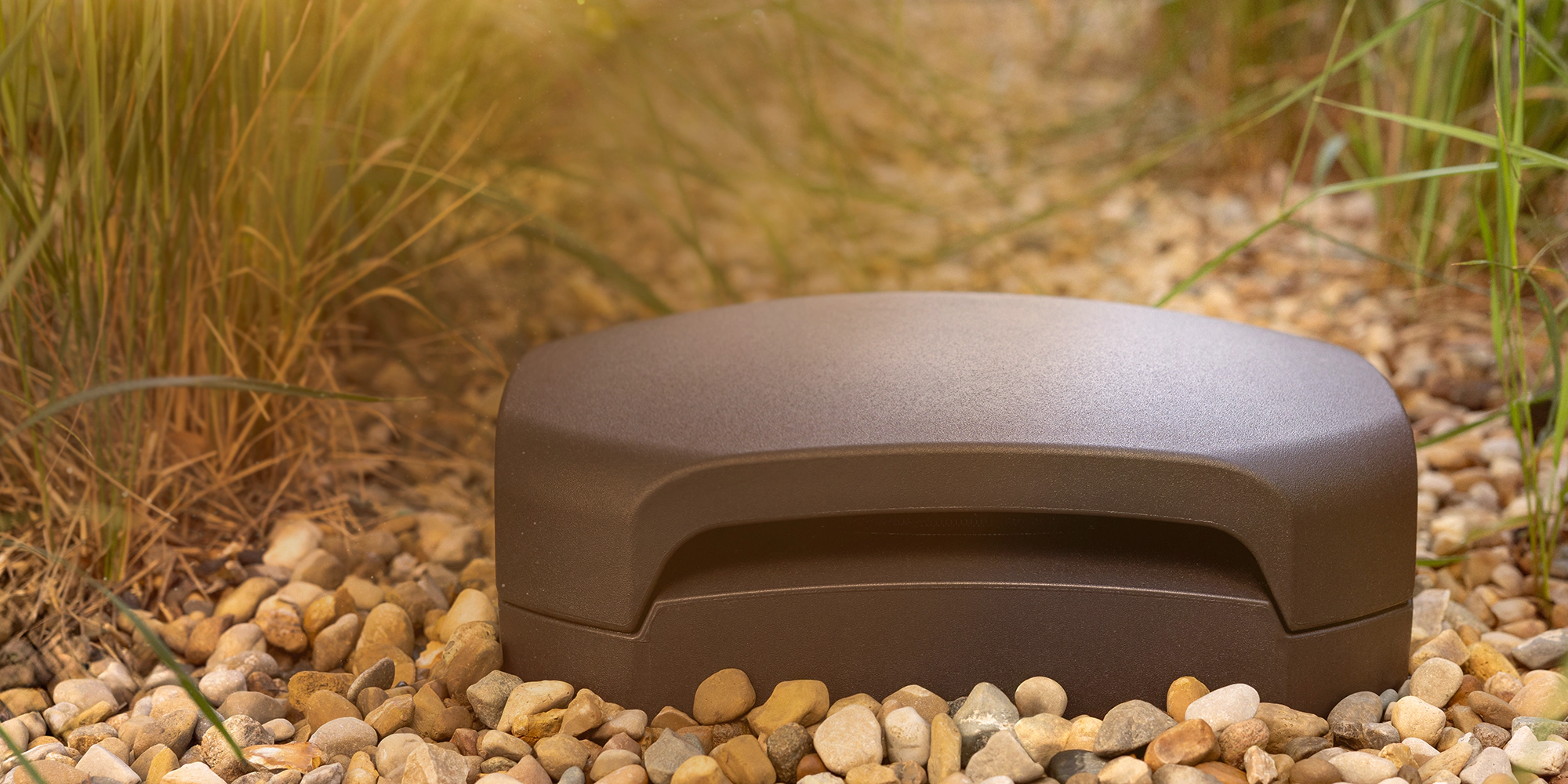 Klipsch-Courtyard-Subwoofer-outside-buried-in-patio-gravel-at-golden-hour-3_2000x1000